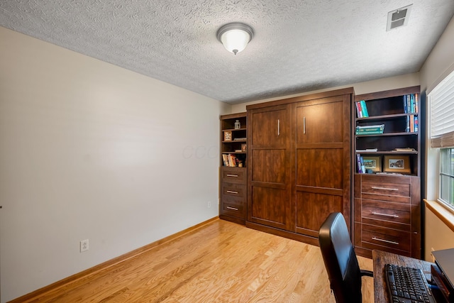 office with a textured ceiling, baseboards, light wood-style flooring, and visible vents