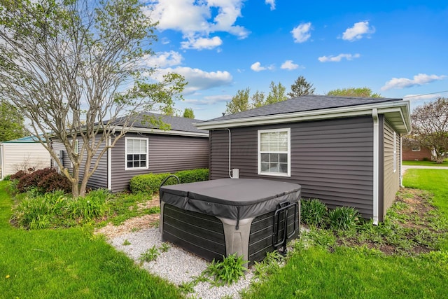 back of house featuring roof with shingles and a hot tub