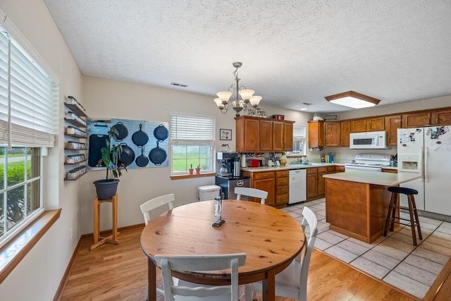 dining space featuring a textured ceiling, a notable chandelier, baseboards, and visible vents