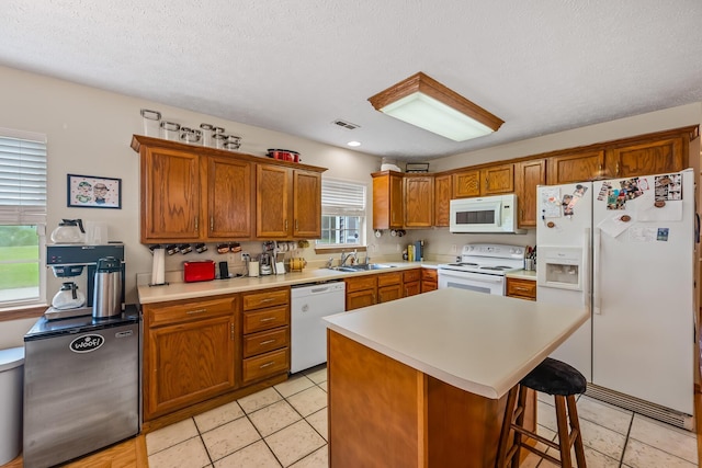 kitchen with brown cabinetry, a sink, white appliances, and light countertops