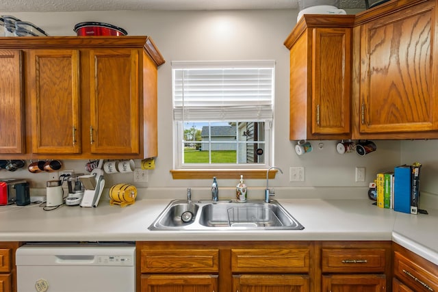 kitchen featuring white dishwasher, a sink, brown cabinets, and light countertops
