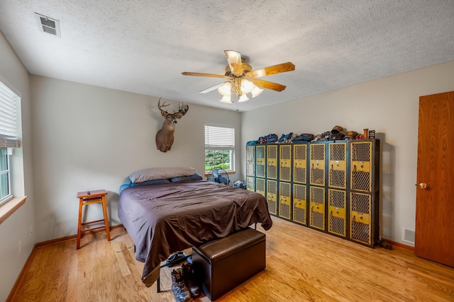 bedroom featuring a textured ceiling, visible vents, and wood finished floors