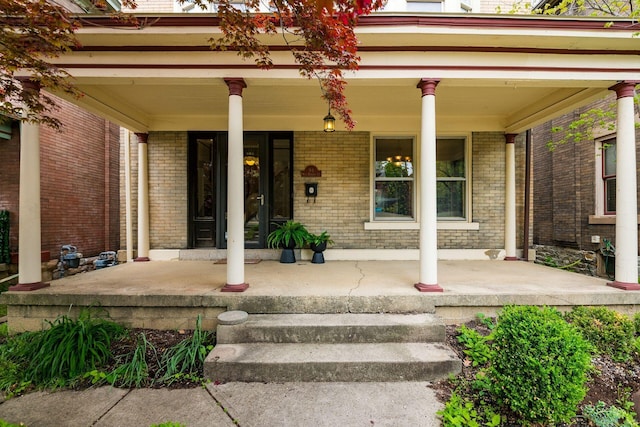 entrance to property featuring covered porch and brick siding