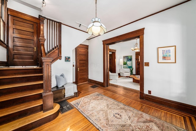 foyer entrance with an inviting chandelier, baseboards, stairway, and wood finished floors