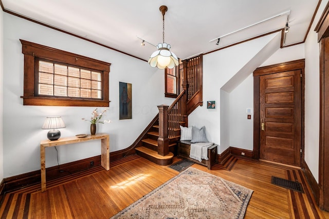 interior space featuring baseboards, rail lighting, wood finished floors, and visible vents