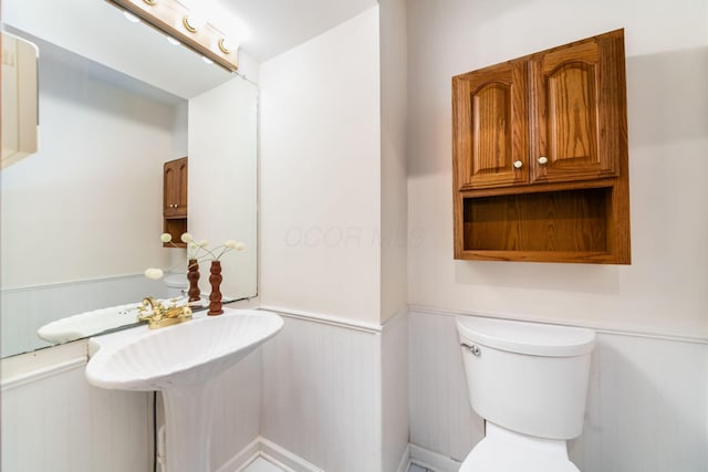 half bathroom featuring toilet and wainscoting