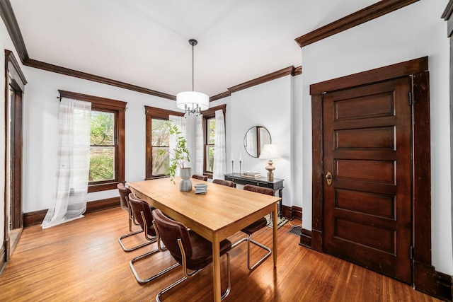 dining area featuring crown molding, baseboards, an inviting chandelier, and wood finished floors