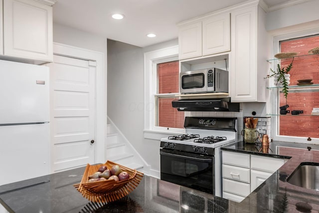 kitchen featuring freestanding refrigerator, white cabinetry, stainless steel microwave, under cabinet range hood, and range with gas cooktop