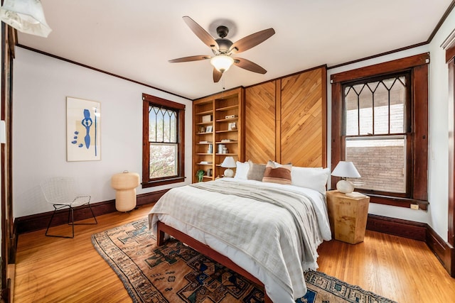 bedroom featuring crown molding, baseboards, ceiling fan, and wood finished floors