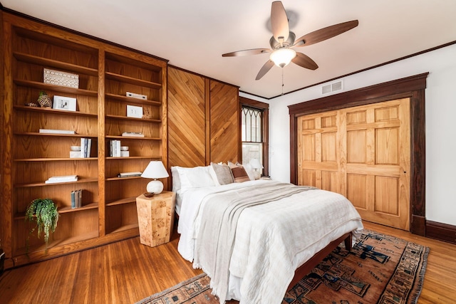 bedroom featuring ceiling fan, baseboards, visible vents, and wood finished floors