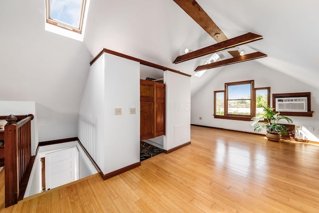 additional living space featuring baseboards, light wood finished floors, lofted ceiling with skylight, and a wall unit AC