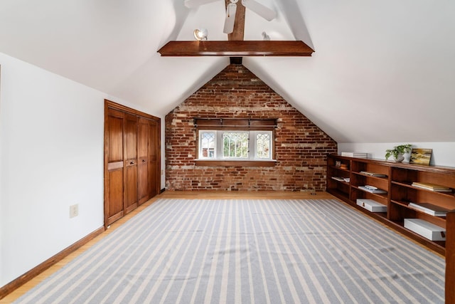 additional living space with light wood-style floors, baseboards, brick wall, and vaulted ceiling with beams