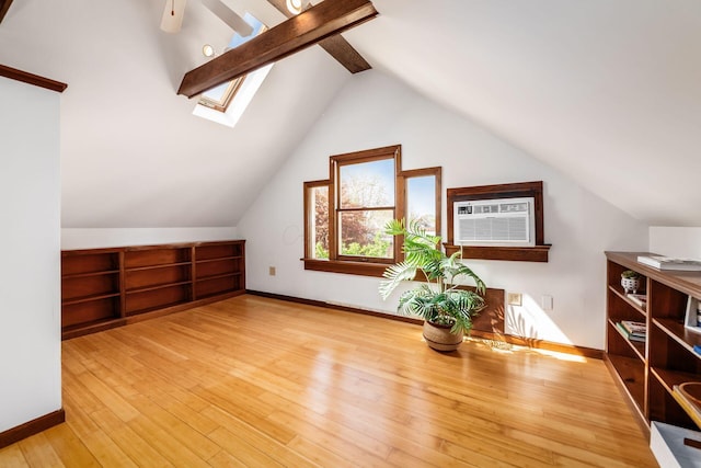 bonus room featuring a ceiling fan, a wall mounted AC, baseboards, lofted ceiling with skylight, and hardwood / wood-style floors