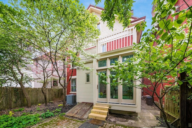 rear view of house with fence, french doors, entry steps, and cooling unit