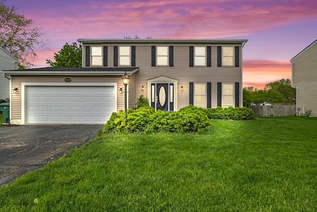 view of front of home with a yard, fence, and driveway