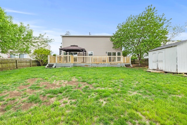 back of house featuring a gazebo, a wooden deck, a shed, a fenced backyard, and a yard