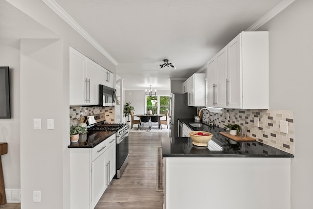 kitchen with decorative backsplash, dark countertops, white cabinets, a sink, and stainless steel appliances