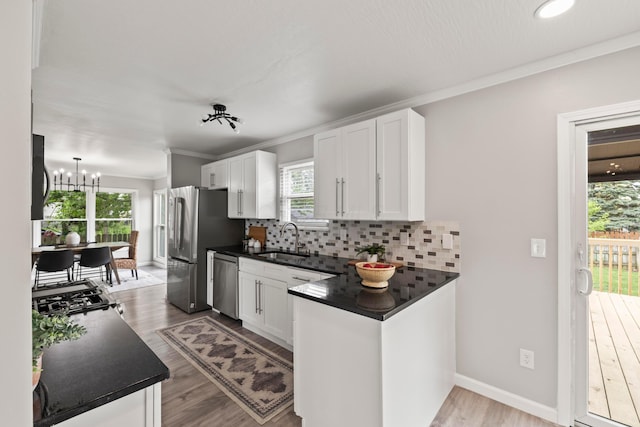 kitchen featuring a sink, dark countertops, stainless steel appliances, and white cabinetry