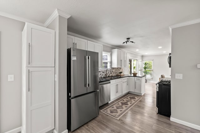 kitchen with ornamental molding, light wood-style flooring, white cabinets, and stainless steel appliances