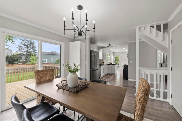 dining space with a chandelier, ornamental molding, and wood finished floors