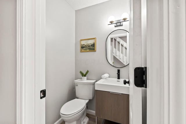 bathroom featuring toilet, baseboards, and a sink