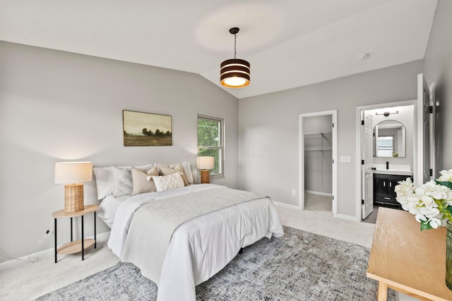bedroom featuring baseboards, lofted ceiling, a spacious closet, and light carpet