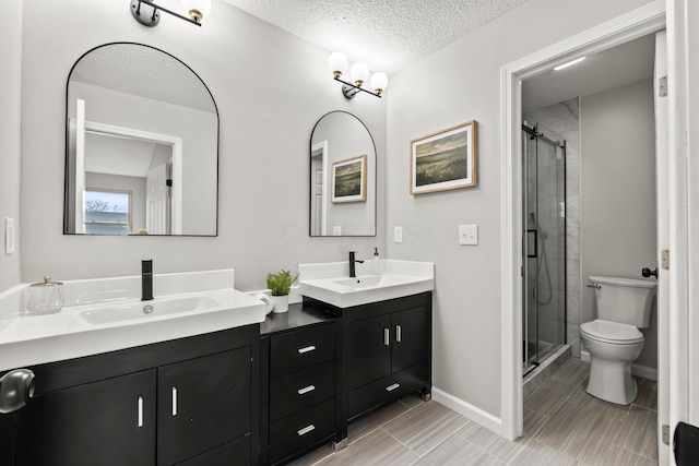 full bathroom featuring double vanity, toilet, a shower stall, and a sink