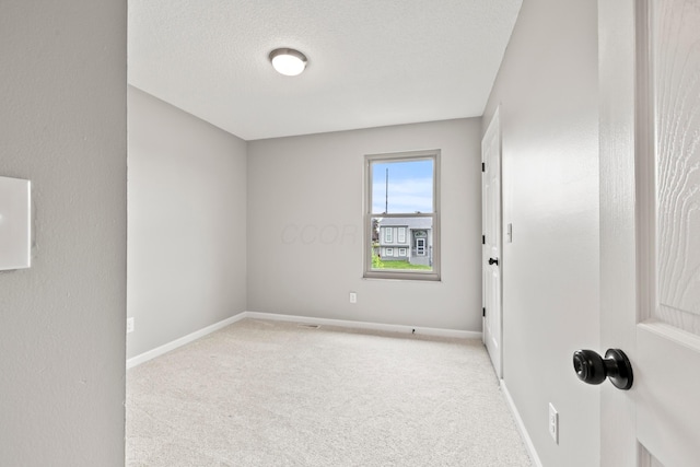 spare room with carpet floors, baseboards, and a textured ceiling