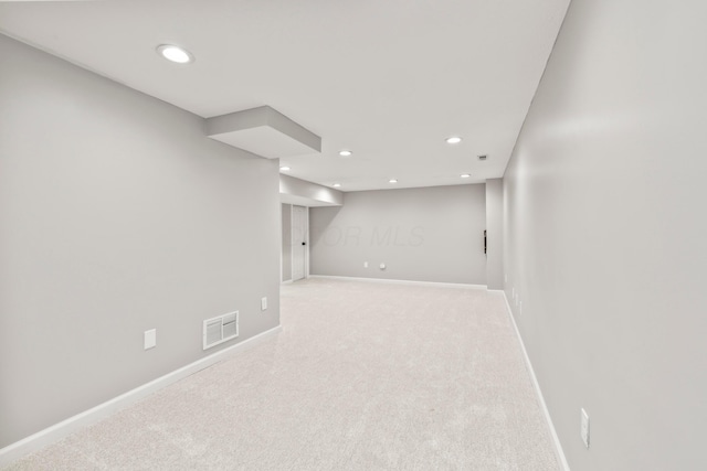 finished below grade area with visible vents, recessed lighting, baseboards, and light colored carpet