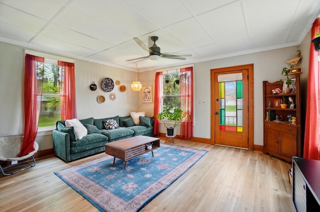 living room featuring baseboards, light wood-style flooring, a ceiling fan, and ornamental molding