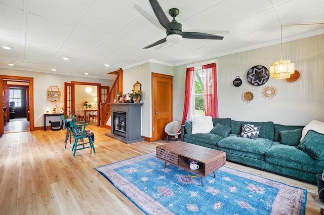 living area featuring crown molding, ceiling fan, baseboards, and light wood-type flooring
