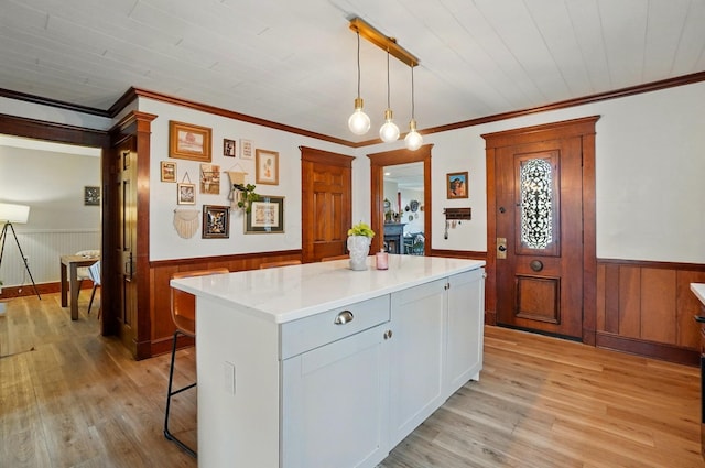 kitchen featuring a wainscoted wall, a kitchen island, and light wood-style flooring