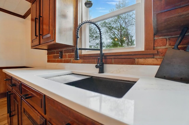 details featuring a wood stove, light countertops, brown cabinets, and a sink
