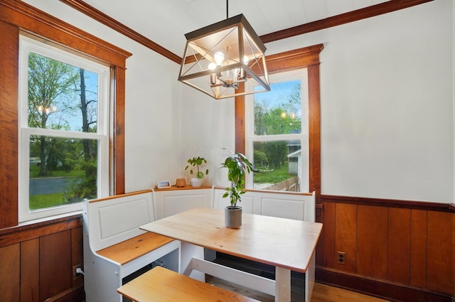 dining space with a chandelier, wood finished floors, wainscoting, and ornamental molding