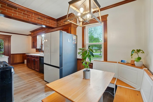 kitchen with stainless steel gas range, freestanding refrigerator, crown molding, and a healthy amount of sunlight