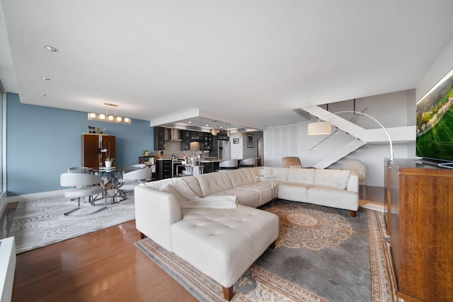 living room featuring baseboards, recessed lighting, wood finished floors, and a notable chandelier