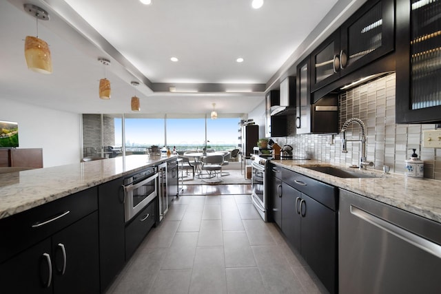 kitchen featuring a sink, appliances with stainless steel finishes, dark cabinetry, and tasteful backsplash