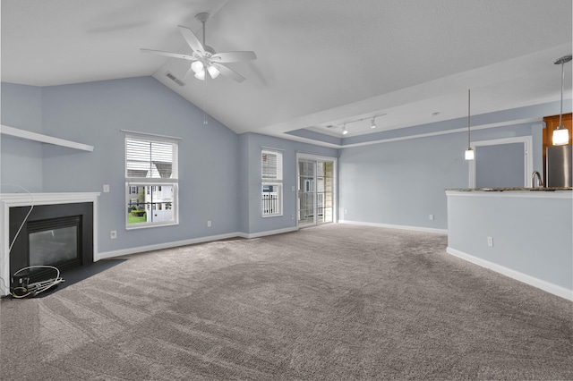 unfurnished living room with visible vents, carpet flooring, a fireplace with flush hearth, and a ceiling fan