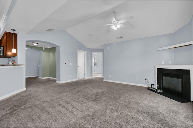 unfurnished living room featuring visible vents, a fireplace with flush hearth, arched walkways, a ceiling fan, and vaulted ceiling