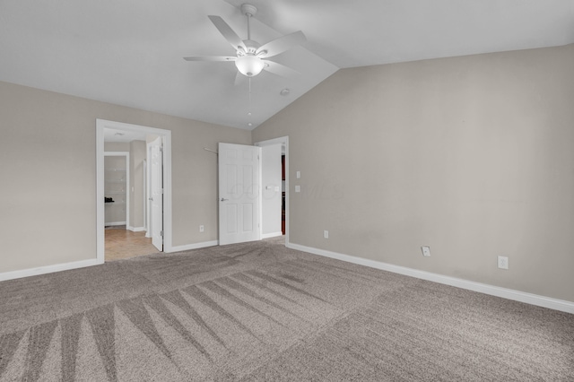 unfurnished bedroom featuring ensuite bath, carpet floors, a ceiling fan, baseboards, and vaulted ceiling