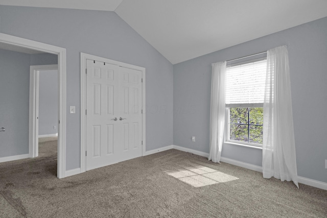 unfurnished bedroom with carpet flooring, baseboards, lofted ceiling, and a closet
