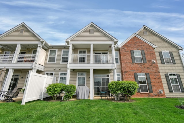 rear view of property featuring brick siding, a yard, and a balcony
