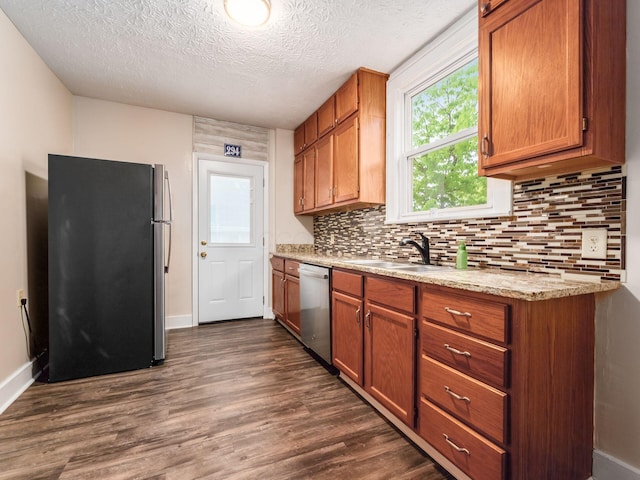 294 E Morrill Ave, Columbus, OH 43207 - kitchen with appliances with stainless steel finishes, decorative backsplash, dark wood-style flooring, brown cabinetry, and a textured ceiling