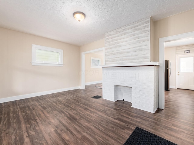 294 E Morrill Ave, Columbus, OH 43207 - unfurnished living room featuring dark wood-type flooring, healthy amount of natural light, a textured ceiling, and baseboards
