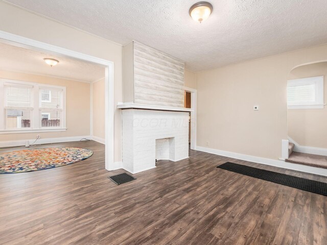 294 E Morrill Ave, Columbus, OH 43207 - unfurnished living room with dark wood-style floors, a textured ceiling, baseboards, arched walkways, and stairs