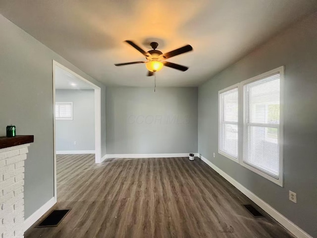 empty room with visible vents, baseboards, dark wood-type flooring, and ceiling fan