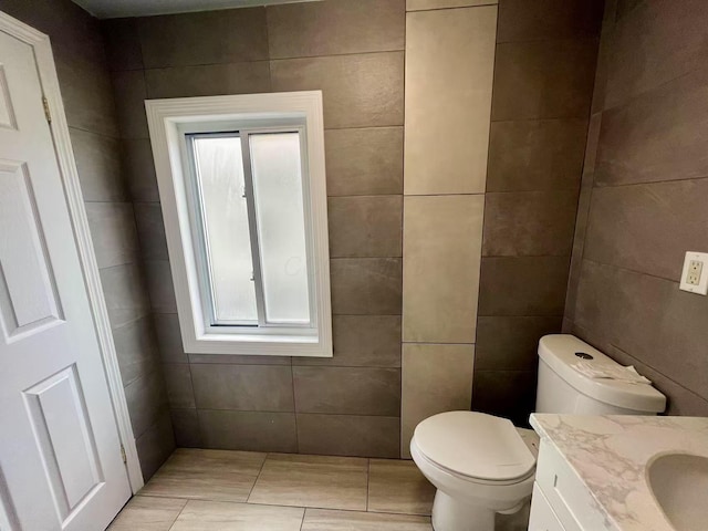 bathroom featuring toilet, tile walls, a healthy amount of sunlight, and vanity