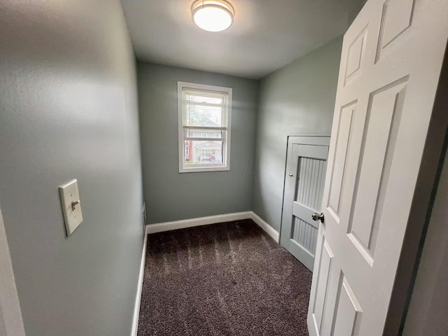 spare room with dark carpet and baseboards