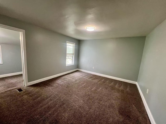interior space with baseboards, visible vents, and dark colored carpet