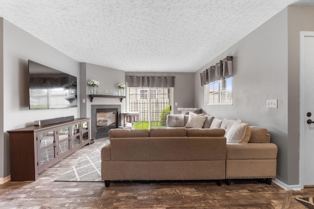 9137 Parkpoint Ln, Lewis Center, OH 43035 - living room featuring a textured ceiling, a glass covered fireplace, wood finished floors, and baseboards
